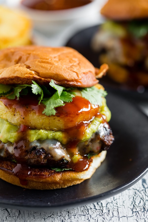 bbq pineapple burger on a black plate.