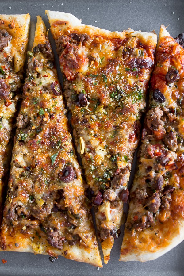 Beef Puttanesca Pizza sliced on a sheet pan. 
