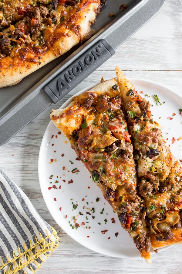 Beef Puttanesca Pizza sliced on a plate. 