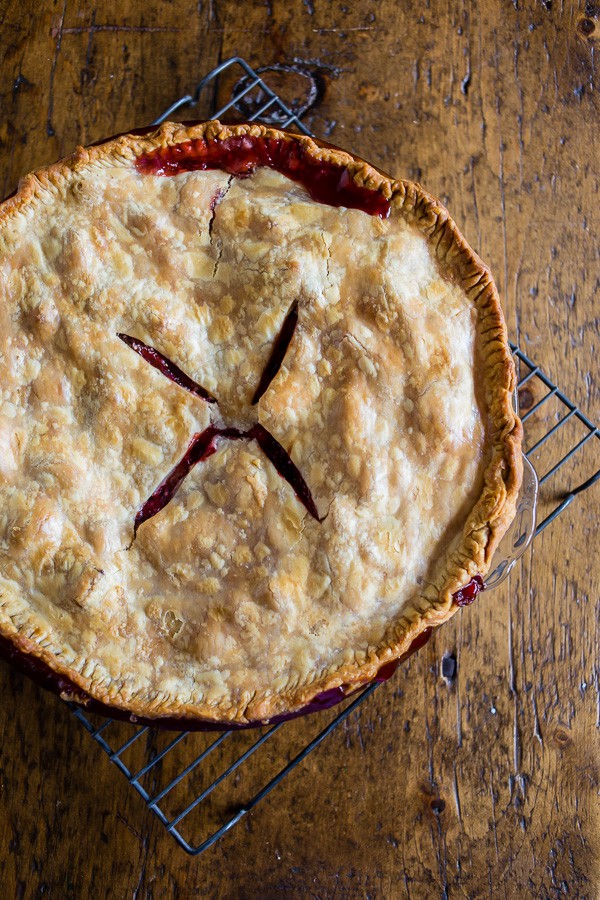 A fully cooked strawberry rhubarb pie on a cooling rack.