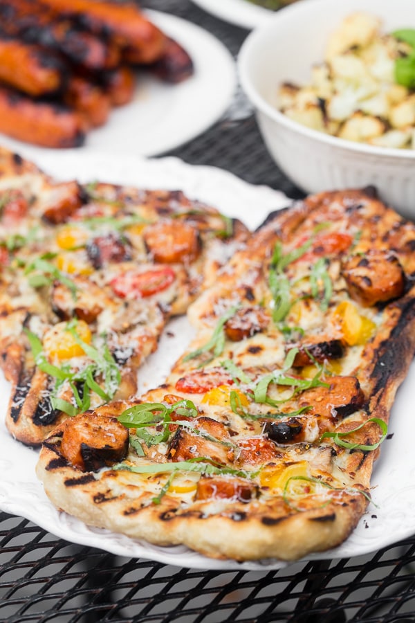 This grilled chicken sausage pizza is made 100% on the grill and is perfect for jazzing up your normal bbq routine. Topped with grilled chicken sausage, mushrooms, cherry tomatoes, mozzarella cheese and lots of fresh basil. You'll want to make this part of your summer as soon as possible!
