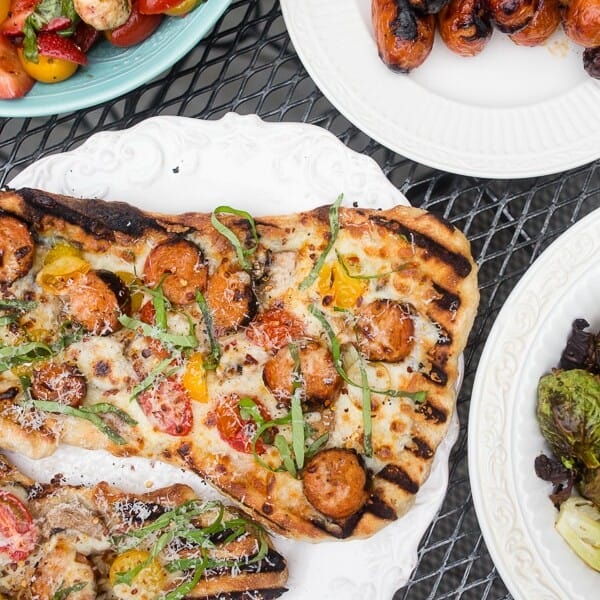 This grilled chicken sausage pizza is made 100% on the grill and is perfect for jazzing up your normal bbq routine. Topped with grilled chicken sausage, mushrooms, cherry tomatoes, mozzarella cheese and lots of fresh basil. You'll want to make this part of your summer as soon as possible!