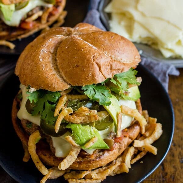 Baja burger on a plate topped with cilantro, crispy onions, and avocado.