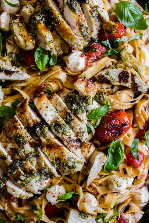 Pesto Chicken Caprese Pasta topped with grilled chicken.