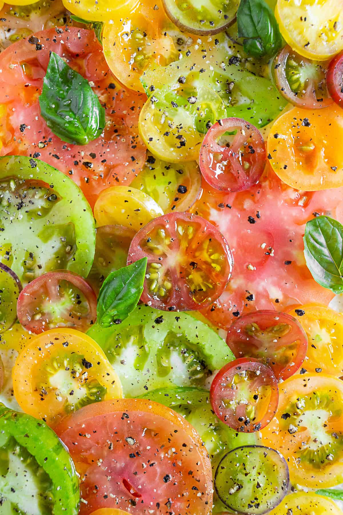 Fresh heirloom tomatoes sliced with fresh basil, black pepper, and kosher salt. 