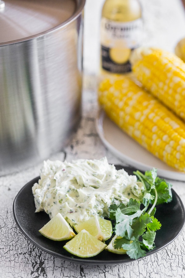 Beer Steamed Corn on the Cob in the background with honey cilantro butter on a plate. 
