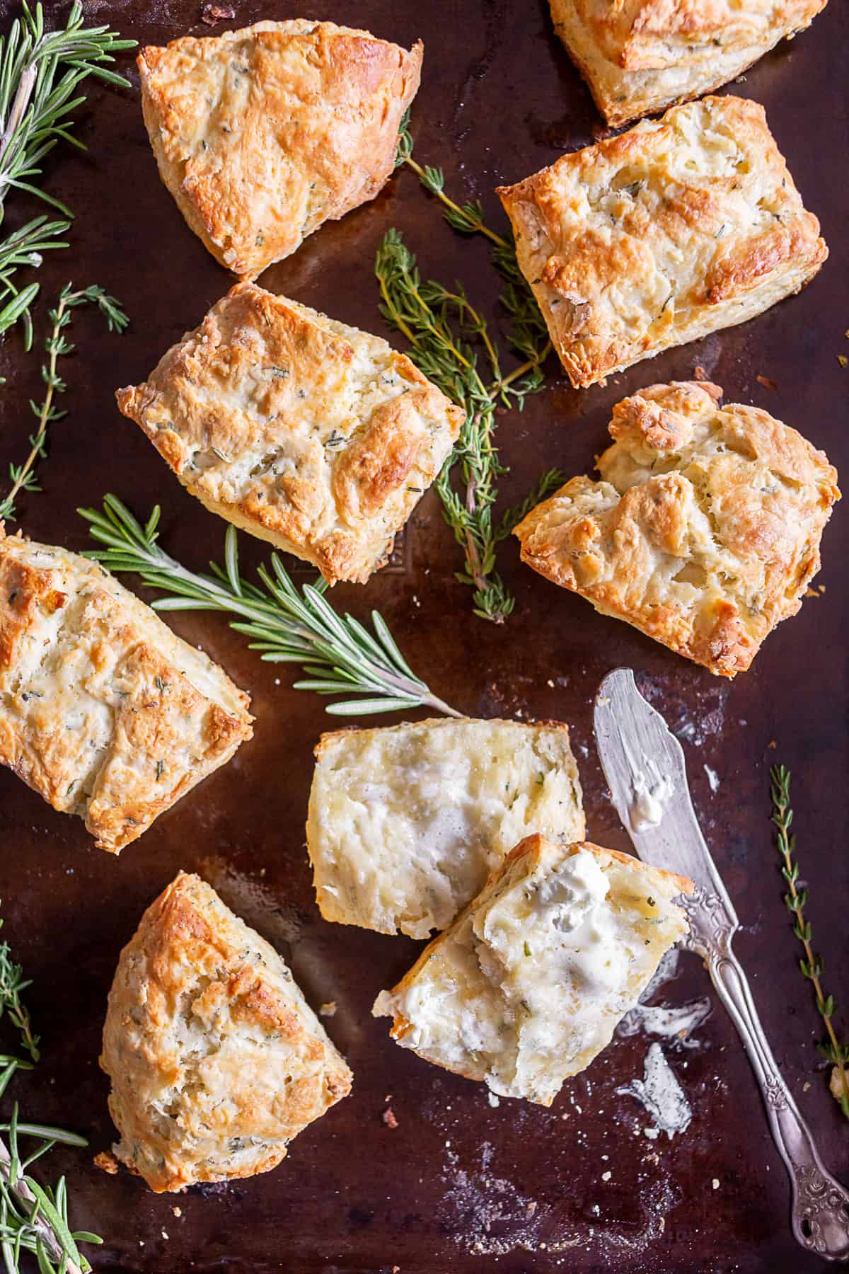Homemade Herb Biscuits on a pan with one cut open and slathered with butter. 