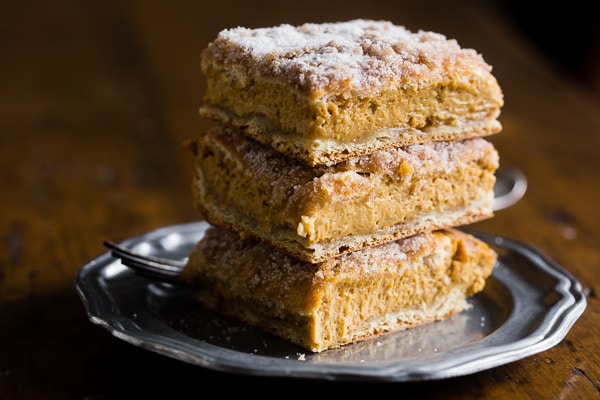 Pumpkin Churro Cheesecake Bars stacked on a plate. 