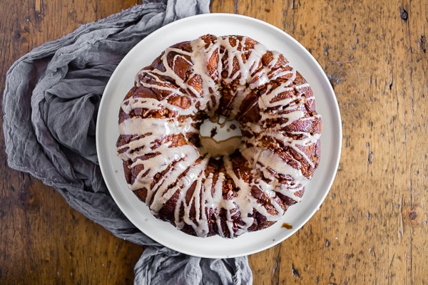 pumpkin spice apple monkey bread on a white plate sitting on a wooden table