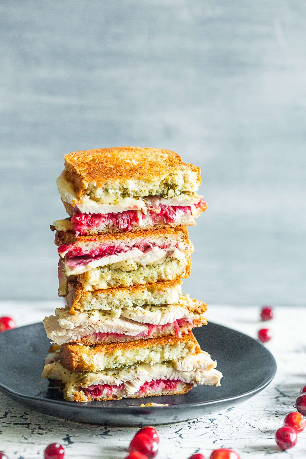 Turkey Cranberry Pesto Panini cut in half and stacked on a plate. 