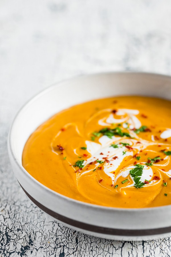 creamy red lentil carrot soup in a white bowl
