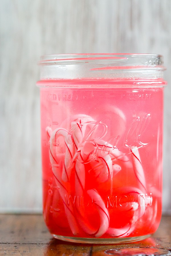 Homemade Candy Cane Vodka in a mason jar with candy canes in the jar. 