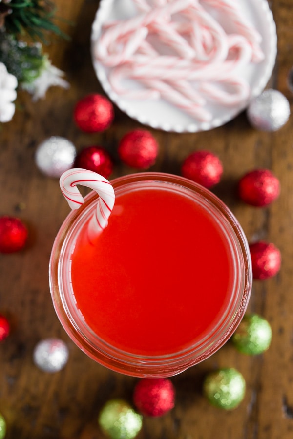 Homemade Candy Cane Vodka in a jar with a little candy cane on the side. 