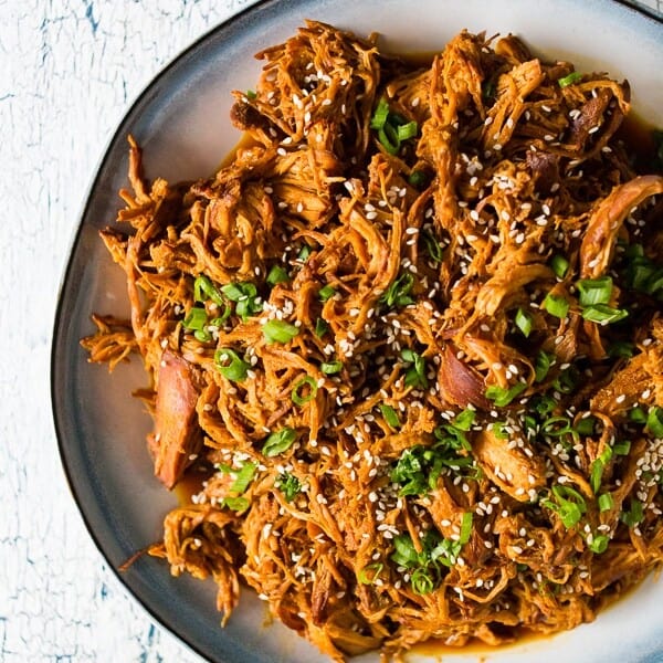 This slow cooker honey soy sriracha pulled chicken is packed full of flavor and made all in the slow cooker. All you need are a few easy ingredients, a slow cooker and 4-6 hours. Serve it over rice, on a bun or straight from the slow cooker!