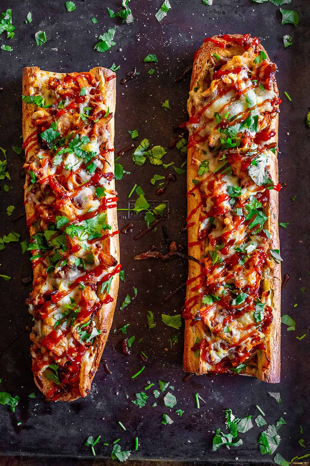 Two french bread pizzas on a baking sheet pan.