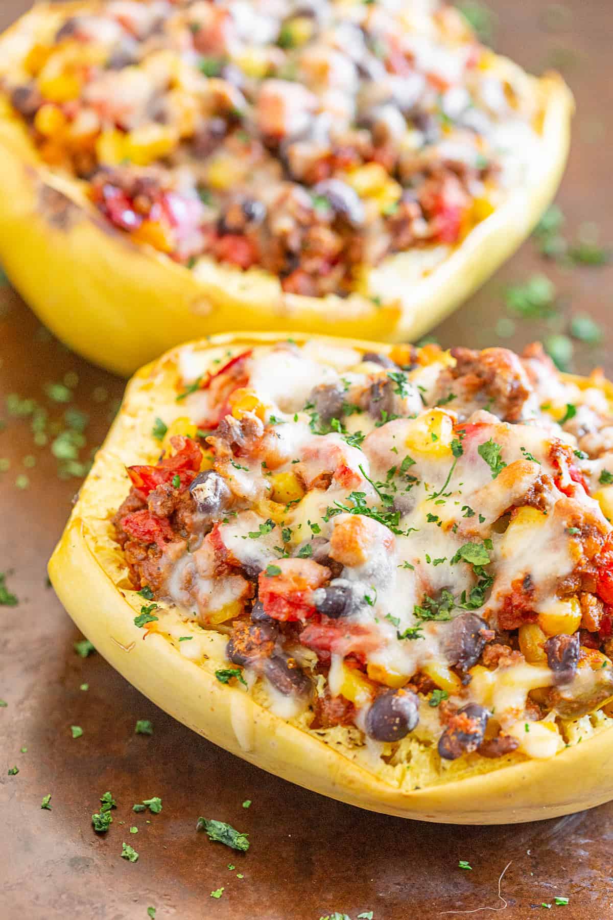 southwest taco stuffed spaghetti squash on a sheet pan topped with cheese