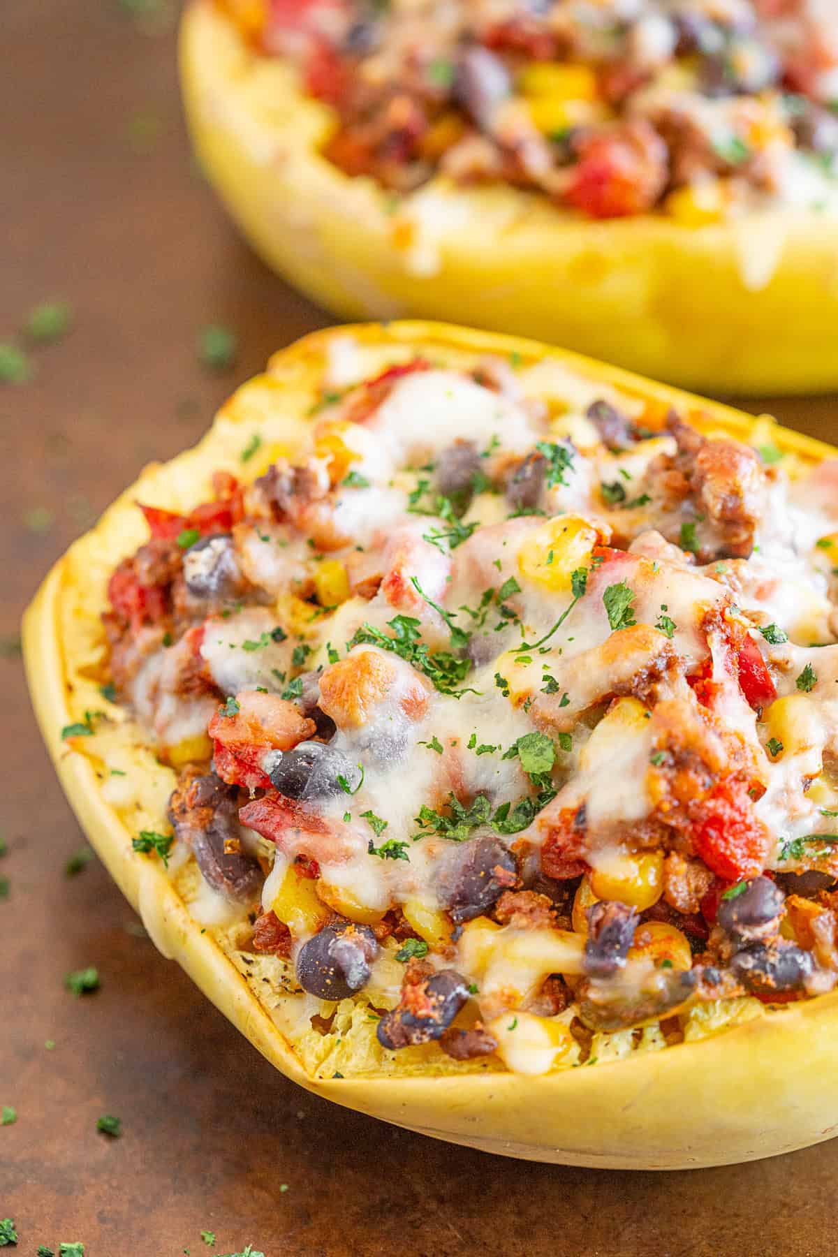 southwest taco stuffed spaghetti squash on a sheet pan topped with cheese and herbs