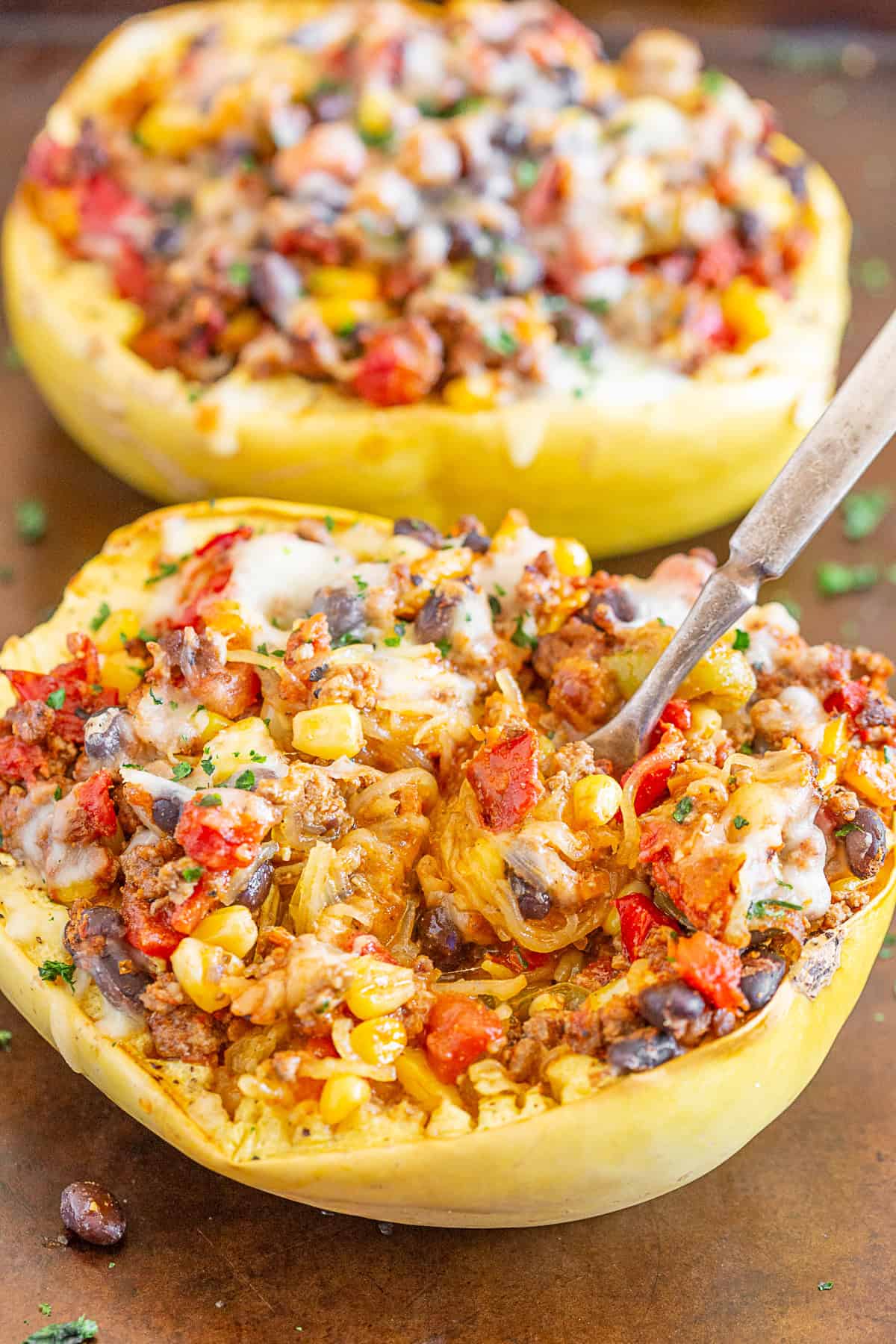 southwest taco stuffed spaghetti squash on a sheet pan with a fork in the middle of the dish