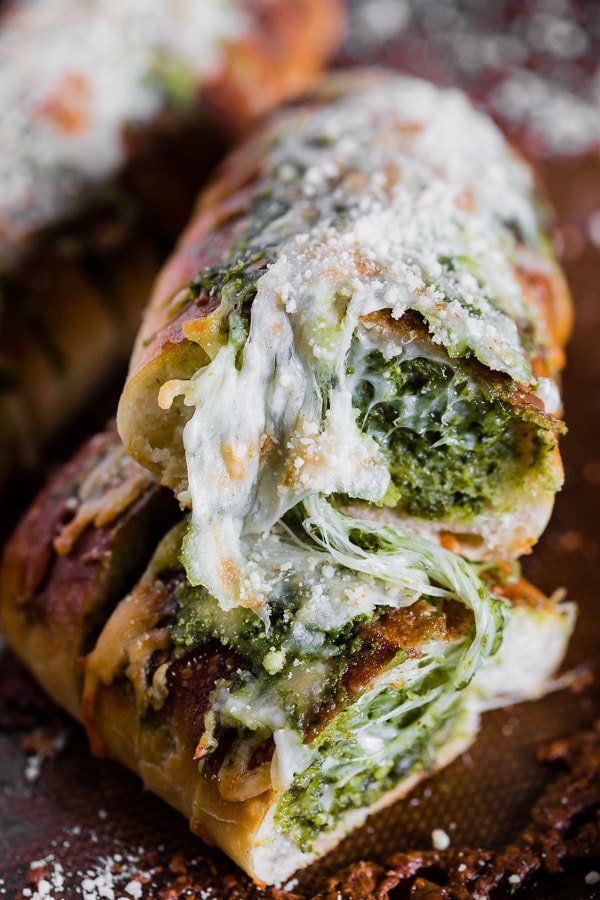 Cheesy Pesto Garlic Bread cut in half to show pesto filling. 