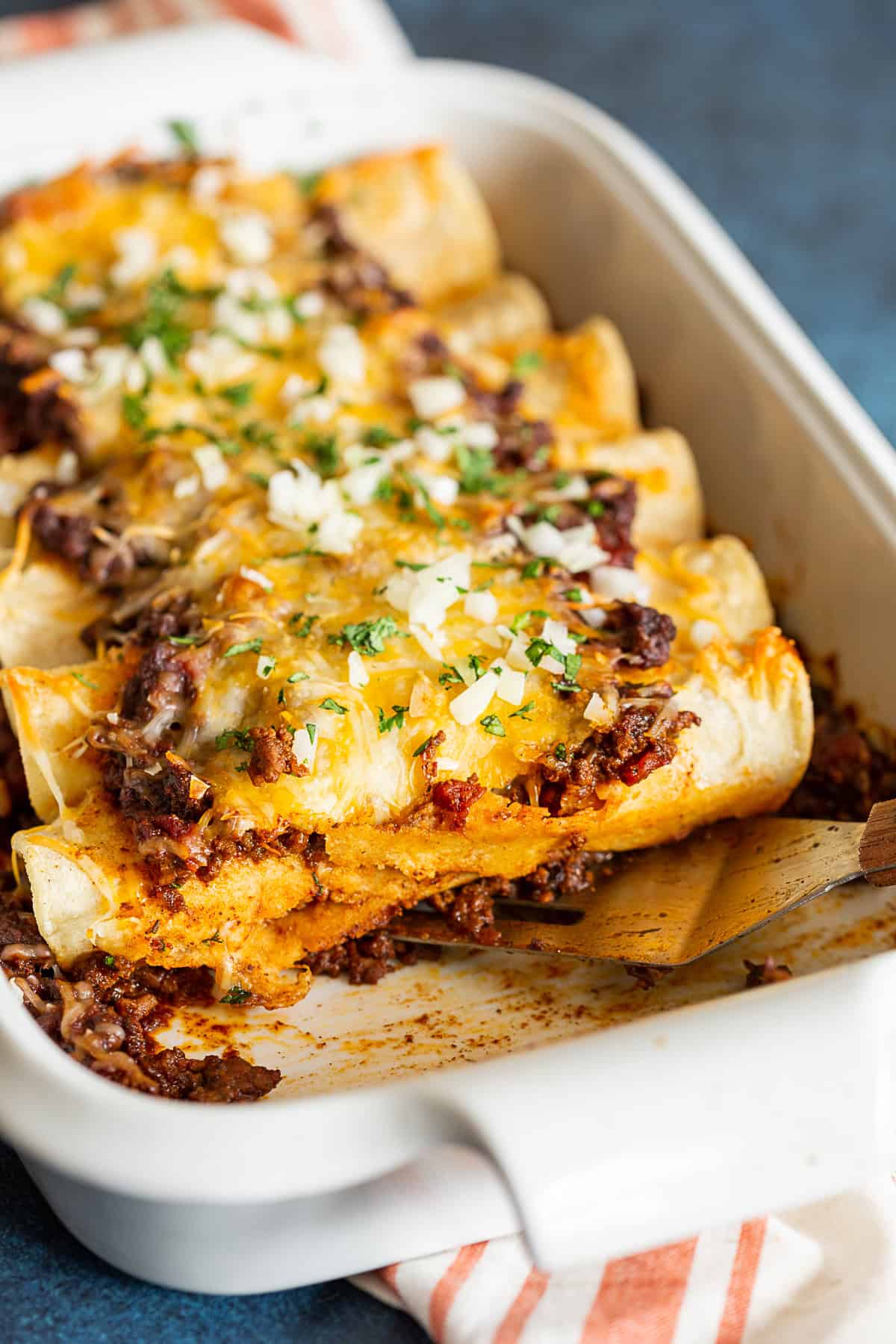 Chipotle Ground Beef Enchiladas in a dish with a spatula. 