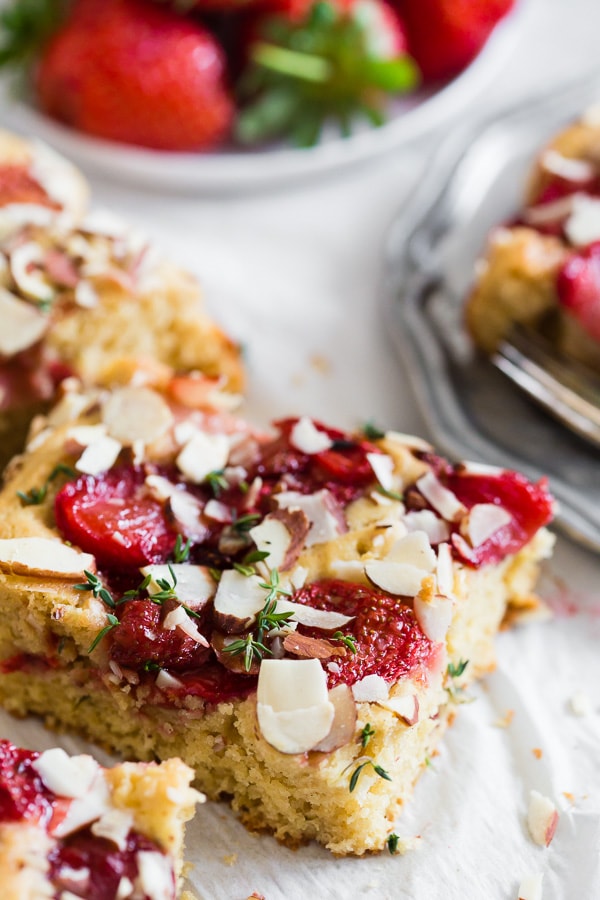 A sliced of Roasted Strawberry Olive Oil Cake on parchment paper. 