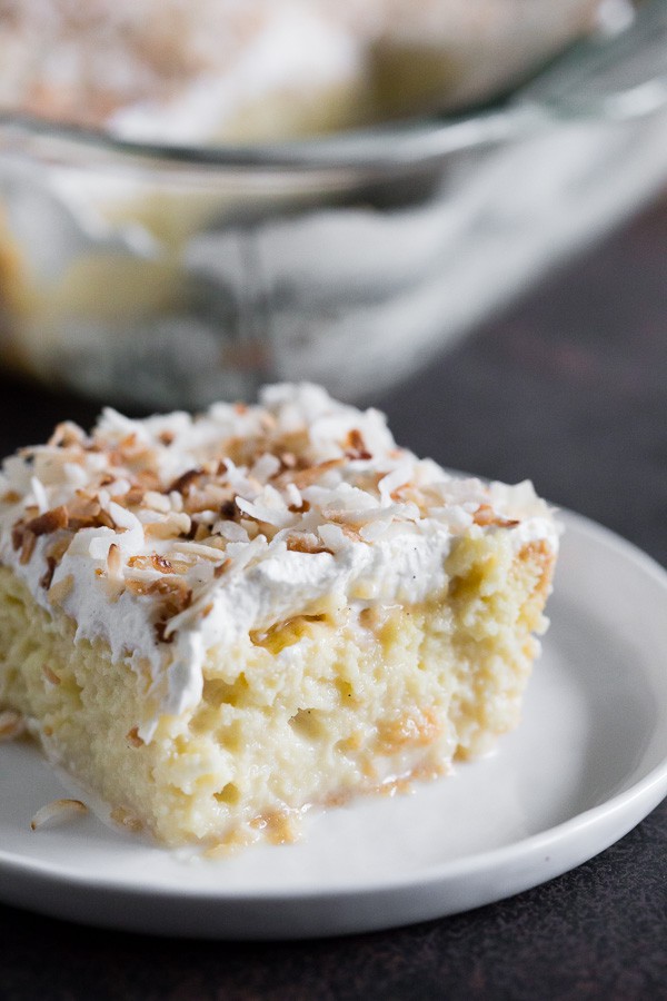 Toasted Coconut Tres Leches Cake sliced on a small white plate. 