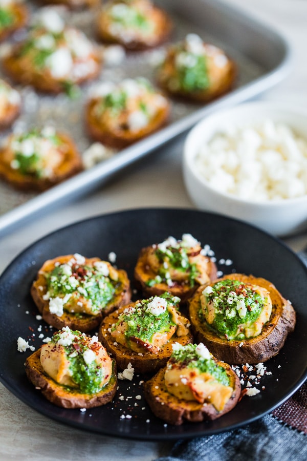 These pesto hummus sweet potato bites are the perfect bite size appetizer. Sumac roasted sweet potato rounds topped with spicy hummus, drizzled with spinach pesto and sprinkled with crumbled feta - how delicious is that!