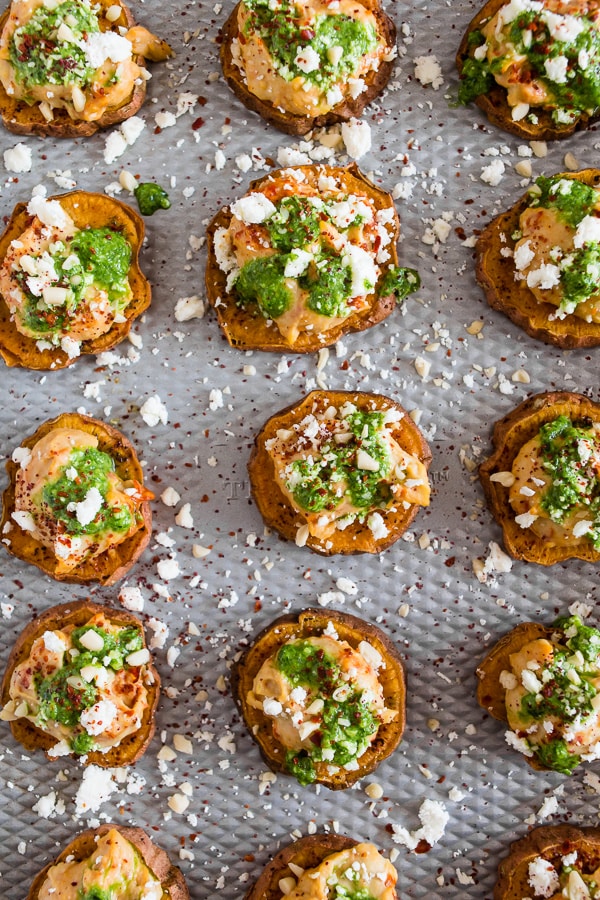 These pesto hummus sweet potato bites are the perfect bite size appetizer. Sumac roasted sweet potato rounds topped with spicy hummus, drizzled with spinach pesto and sprinkled with crumbled feta - how delicious is that!