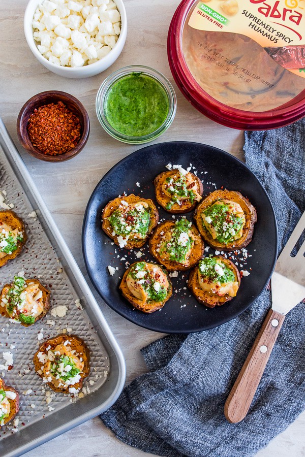 These pesto hummus sweet potato bites are the perfect bite size appetizer. Sumac roasted sweet potato rounds topped with spicy hummus, drizzled with spinach pesto and sprinkled with crumbled feta - how delicious is that!
