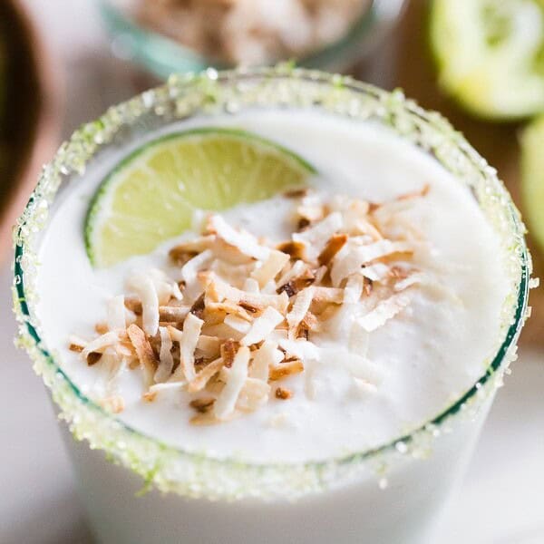 This coconut lime frozen margarita is just what your summer ordered! PACKED full of sweet coconut flavor and jazzed up with zippy lime juice. Instead of salt, I opted to rim the cocktail with lime sugar and top it with toasted coconut.