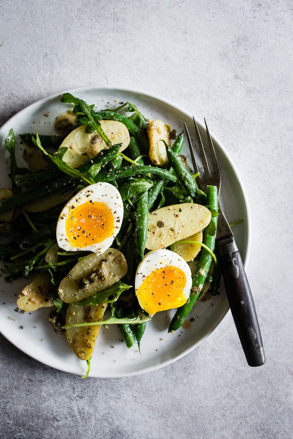 This tangy green bean potato salad is the perfect combination of buttery fingerling potatoes, crunchy blanched green beans, peppery arugula and soft boiled eggs all tossed in a creamy Dijon and caper vinaigrette. It's tangy, perfect for hot summer nights and makes an amazingly fast and easy meatless dinner! 