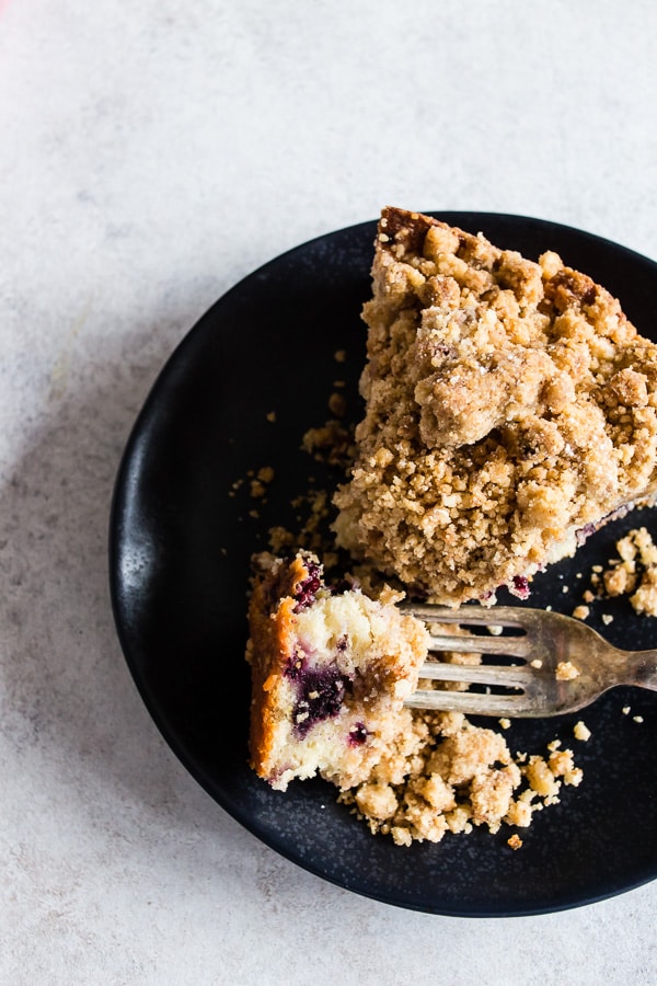 A slice of mixed berry coffee cake on a plate with a fork. 