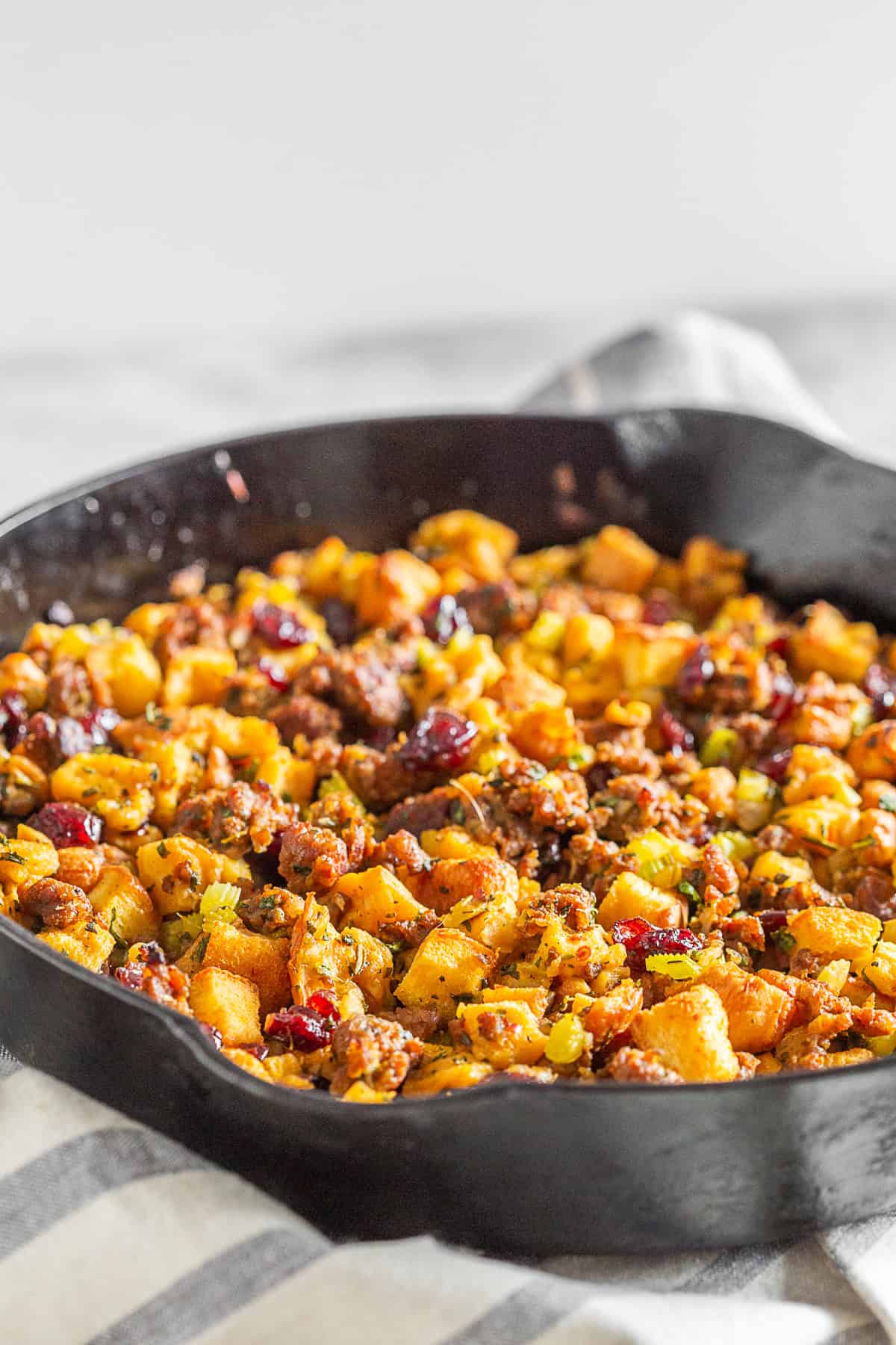 Potato Bread Sausage Cranberry Stuffing in a skillet with fresh herbs on top. 
