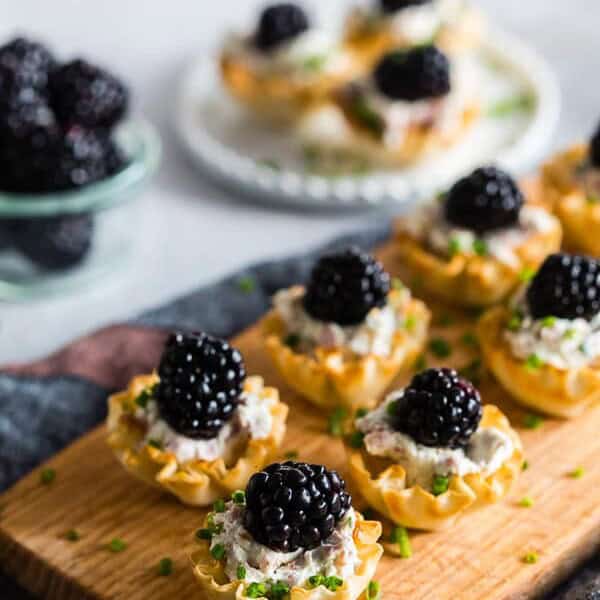 These goat cheese prosciutto blackberry phyllo bites are a delicious addition to any holiday party - tangy goat cheese mixed with cream cheese, chives, crispy prosciutto and topped with a fresh blackberry. This fun appetizer is the perfect little 2 bite treat! 