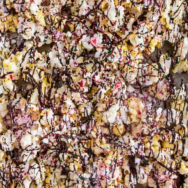 This peppermint bark popcorn is the EASIEST Christmas candy snack ever! Lightly buttered popcorn topped with white chocolate, dark chocolate, crushed candy canes, and sprinkles. You'll love this flavor packed snack!