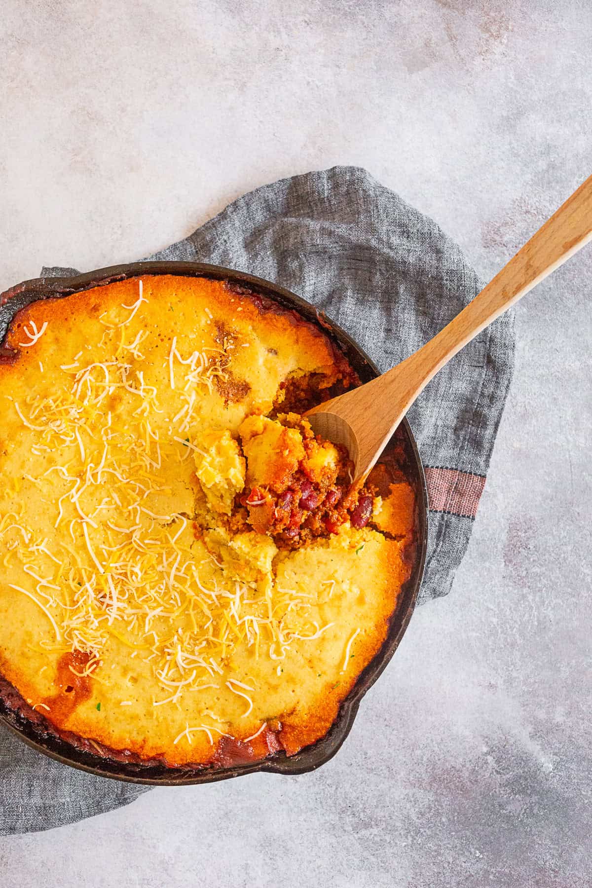 Buttermilk Cornbread Topped Chili being spooned out of the skillet. 