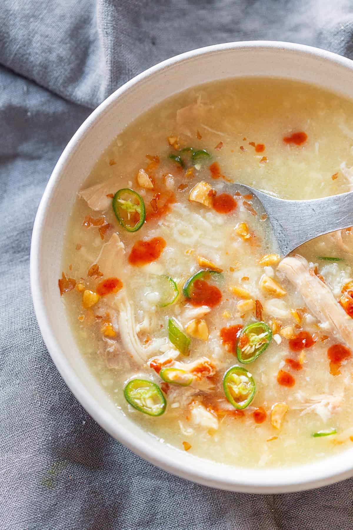 Instant Pot Asian Chicken and Rice Soup topped with peanuts, sriracha, and chilies.