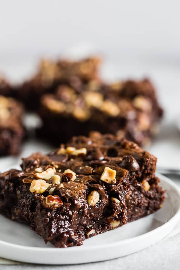 A cut Hazelnut Buckwheat Brownie on a small white plate. 