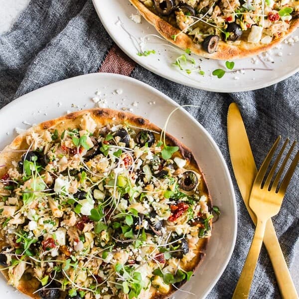 This Mediterranean tuna salad flatbread is the perfect protein and vegetable packed meal. Delicious albacore and yellowfin tuna mixed with lemon, parsley, sun dried tomatoes, capers, black olives, shallots, dill and artichoke hearts all piled high on a whole wheat pita and sprinkled with feta cheese and micro greens. You'll love this simple flavor packed lunch or dinner. 