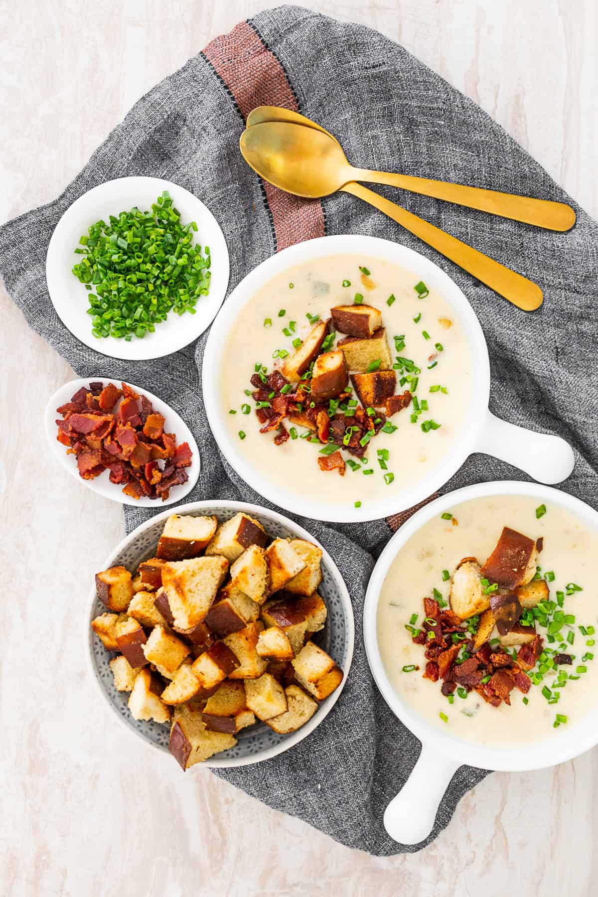 Beer Cheese Soup on a table in 2 bowls with toppings on the side. 