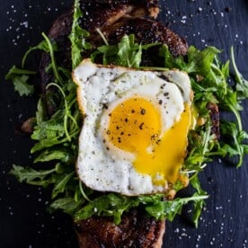fried egg topped steak with arugula