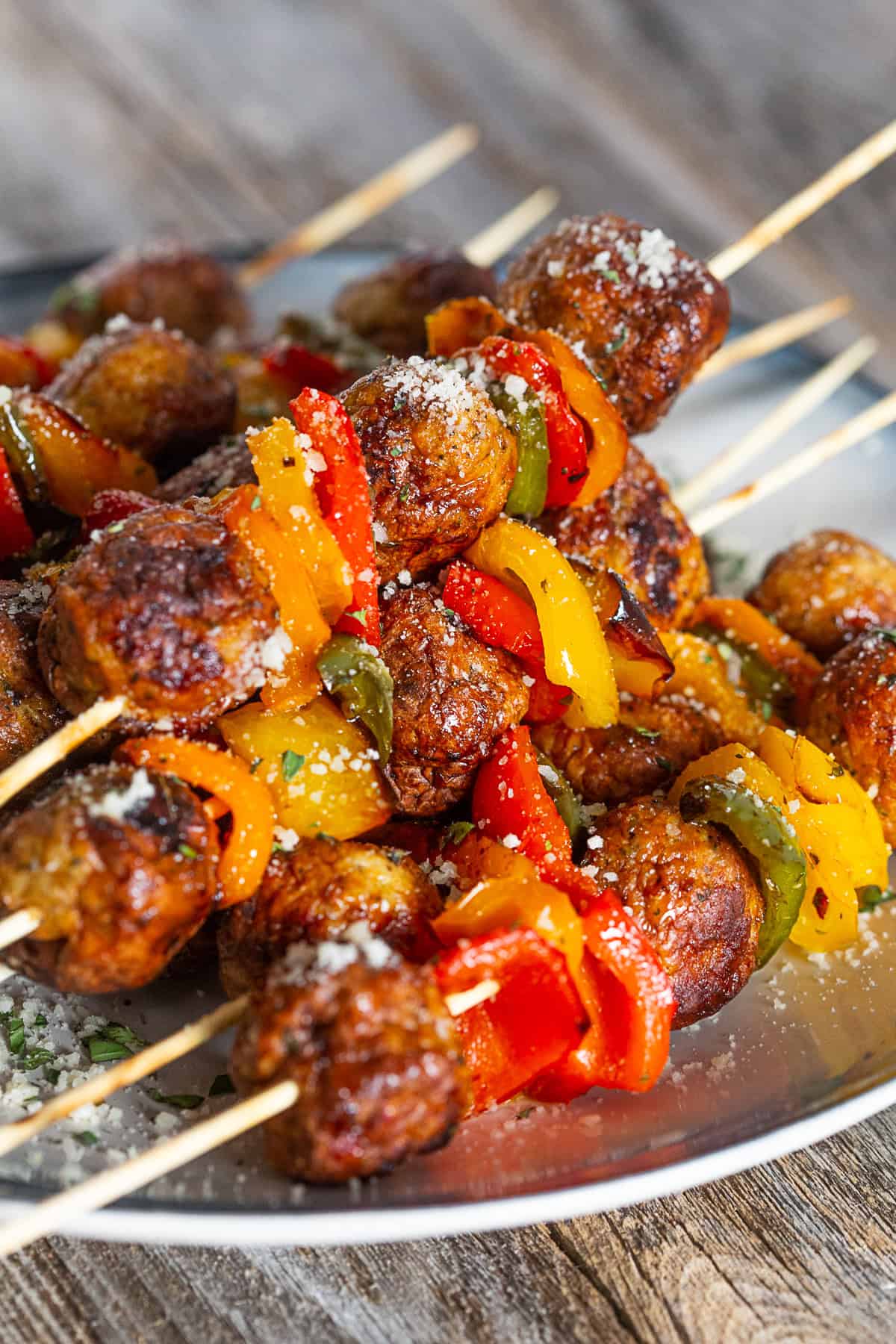 Grilled Chicken Meatball Skewers on a plate sprinkled with Parmesan cheese. 
