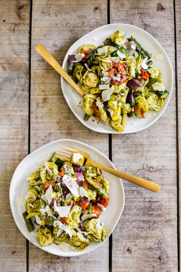 Roasted Vegetable Tortellini Salad served on 2 plates sitting on a wooden table. 