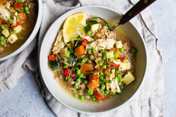 Lemon Chicken Vegetable Farro Soup served with a lemon wedge.