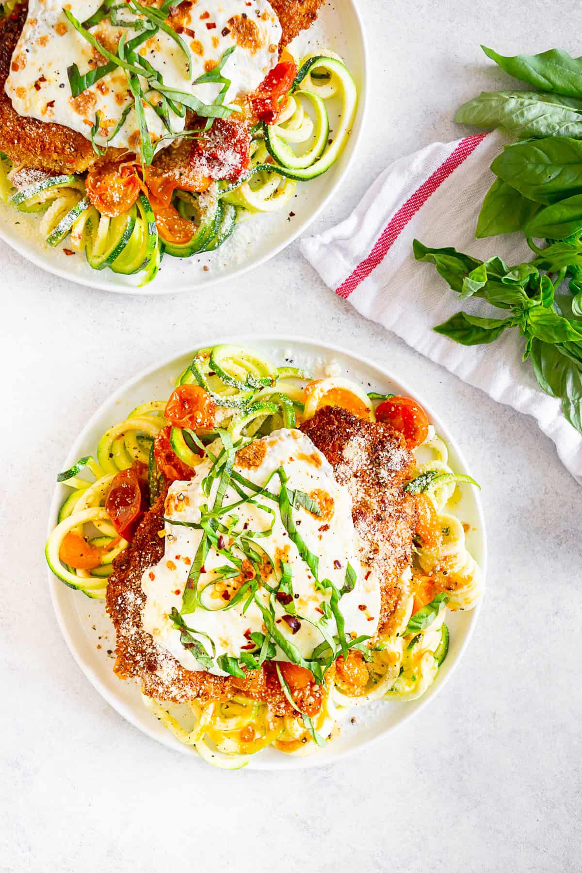 Summer Chicken Parmesan with Zoodles on a plate topped with basil.