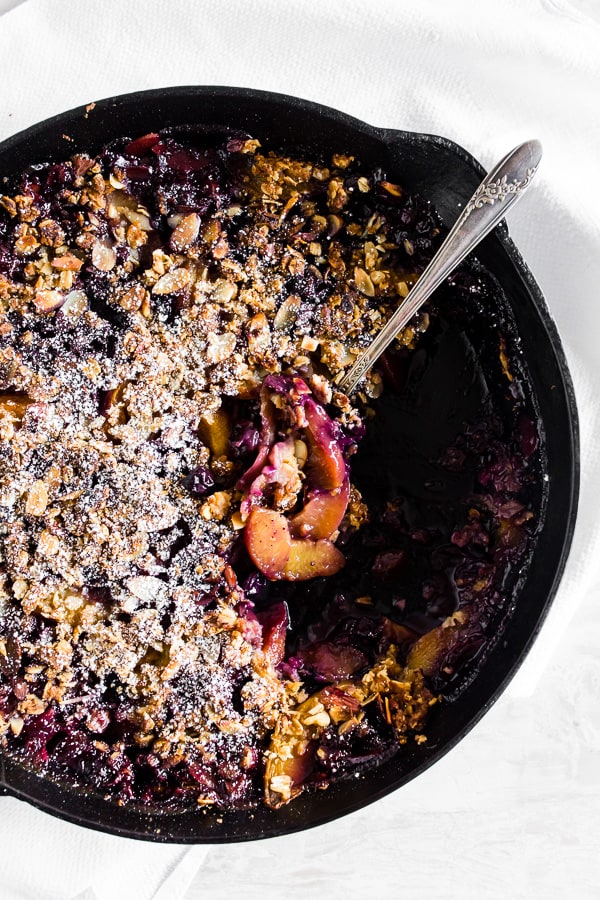 blueberry peach cast iron crisp with a spoonful taken out.