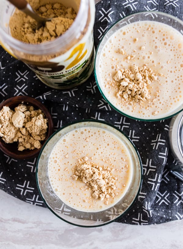 Overhead view of two smoothies with peanut butter powder sprinkled on top.