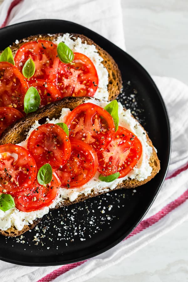 tomato ricotta toast on a black plate. 