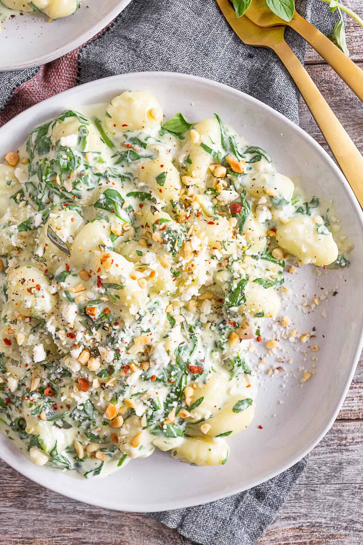 creamy gorgonzola gnocchi on a plate topped with sprinkled pine nuts. 