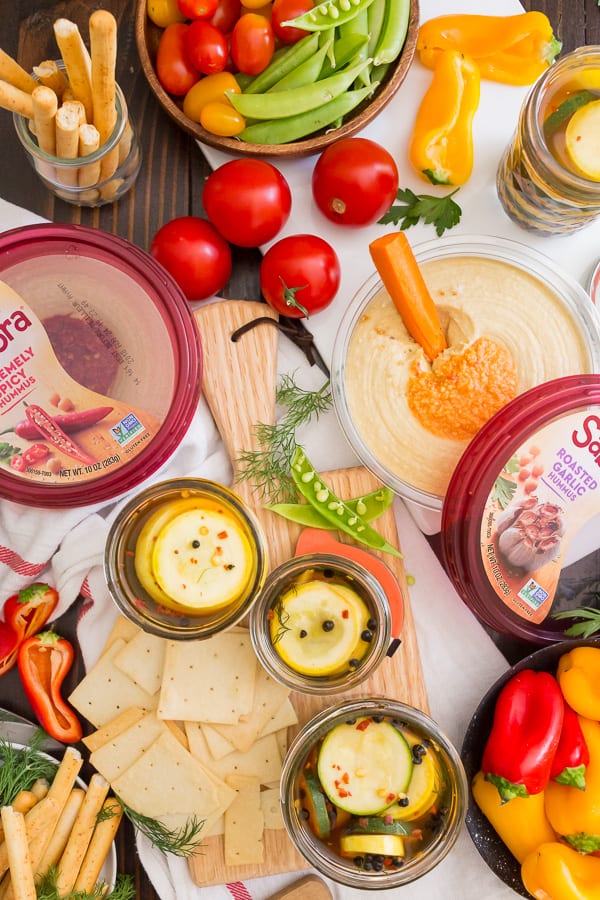 sweet and spicy zucchini pickles on snack board with hummus and vegetables